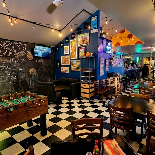 Scrappy's Pizza interior with foosball, chalkboard wall, checkered floor, and dining tables.